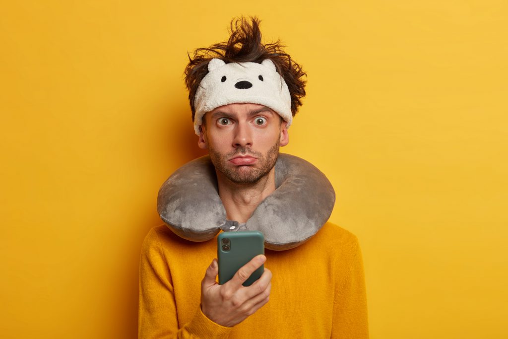 A man with a monkey hat and holding a cell phone.